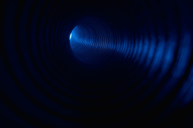 Fluoreszierender Hintergrund Unscharfes Neonlicht Scheinwerferbeleuchtung Defokussierter LED-Leuchtstrahl in blauer Farbe in geripptem Texturwirbeltunnel auf dunkelschwarzem Kopierraum