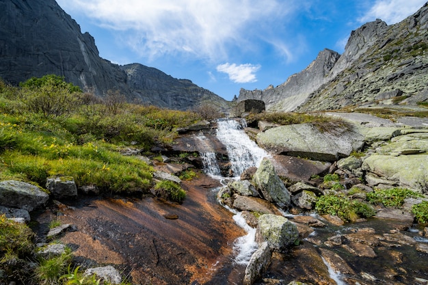 Fluss, der bunten Wald des Herbstes durchfließt. Schöner Fallfluß mit Felsen und Bäumen