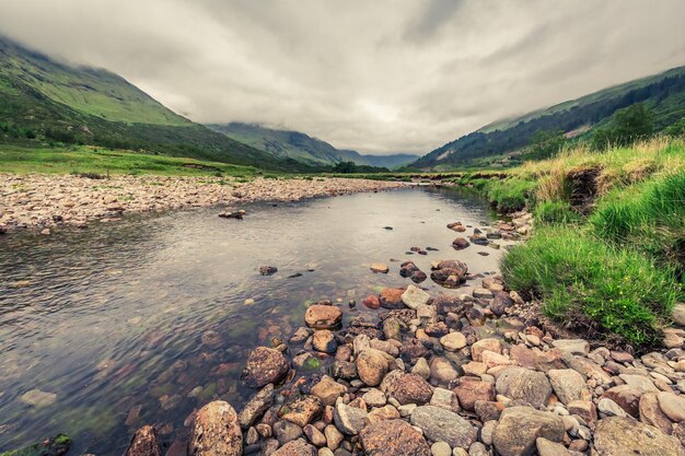 Fluss und Berg und Steine an einem nebligen Tag Schottland