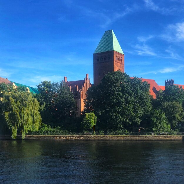 Foto fluss von bäumen und gebäuden gegen den blauen himmel