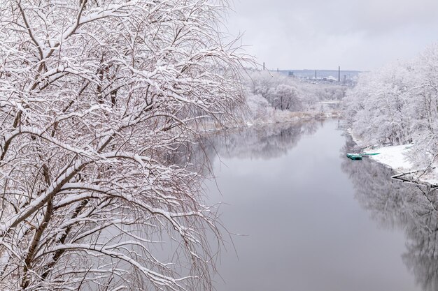 Flusslandschaft im Winterwald mit Bäumen, die mit Neuschnee bedeckt sind. Verschneite Winterflusslandschaft