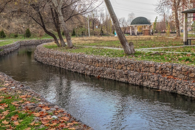 Flussufer verstärkt mit Steinen in einem Metallgitter im Park im Herbst