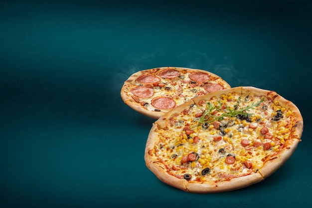 Flutuante, fumando pizzas italianas em um fundo turquesa com diferentes coberturas. Pizza recém-assada com espaço de cópia para texto ou desenho