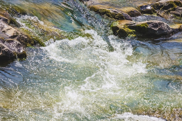 Fluxo de água tempestuoso perto de seixos em um rio de montanha