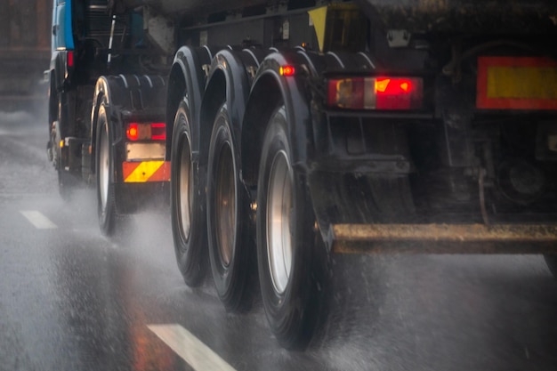 Fluxo de respingos de água da chuva das rodas do caminhão pesado se movendo rapidamente na cidade à luz do dia com foco seletivo