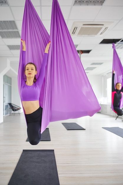 Fly yoga, entrenamiento en grupo femenino, colgando de hamacas. Se mezclan ejercicios de fitness, pilates y danza. Mujeres en entrenamiento de yoga