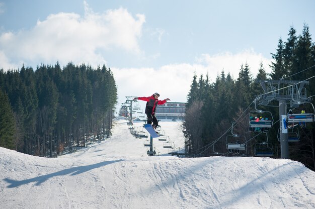 Flying snowboarder en salto desde la ladera de las montañas