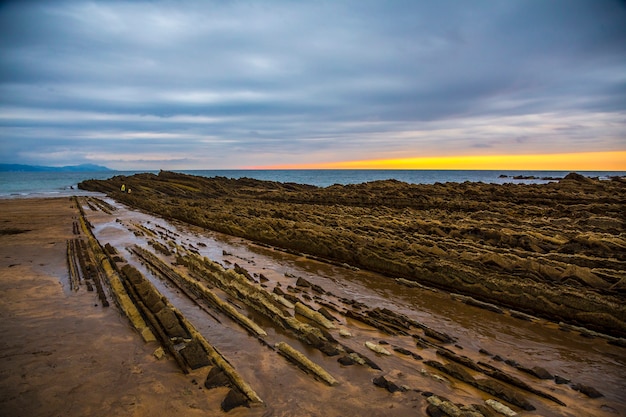 El flysch de Itzurun en la Zumaia con el mar de fondo con la puesta de sol de fondo. España