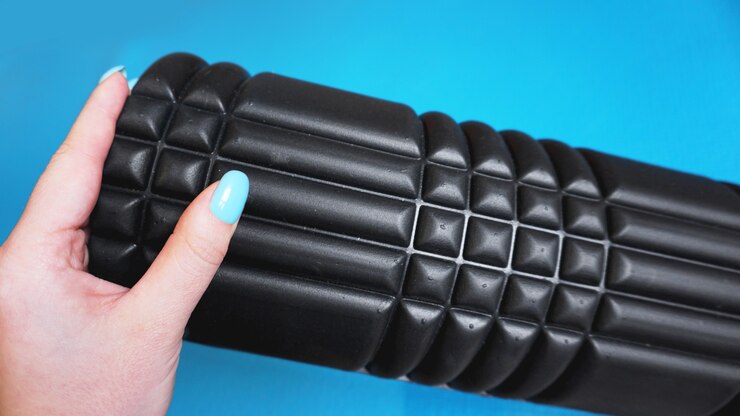 Foto foam roller gym fitness equipment fundo azul auto liberação miofascial - mfr. a mão segura um rolo. como escolher equipamentos para esportes