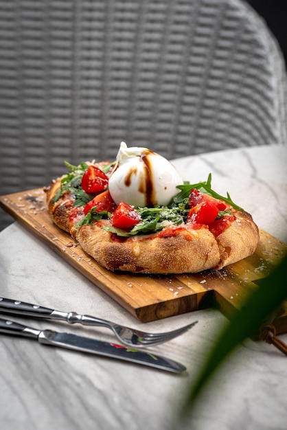 Focaccia italiana con burrata y flor de calabacín con tomates cherry y composición de vista plana de jamón sobre fondo negro