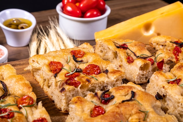 Foto focaccia italiana tradicional com tomate cereja, azeitonas pretas e alecrim.