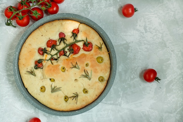 Foto focaccia italiana tradicional con tomate, aceitunas y romero.