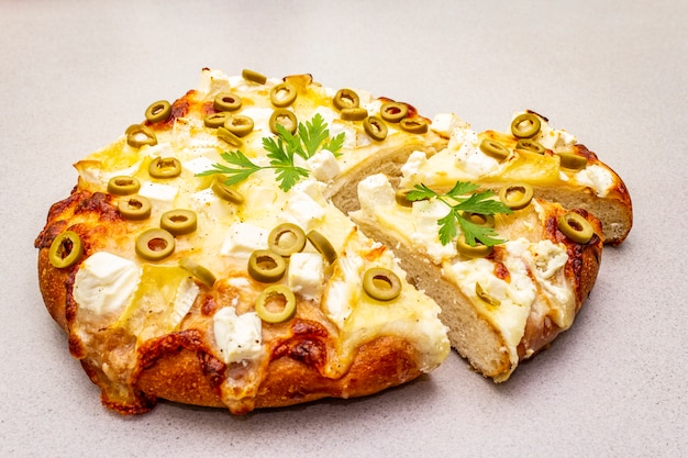 Focaccia italiana con tres tipos de queso, aceitunas verdes y perejil.