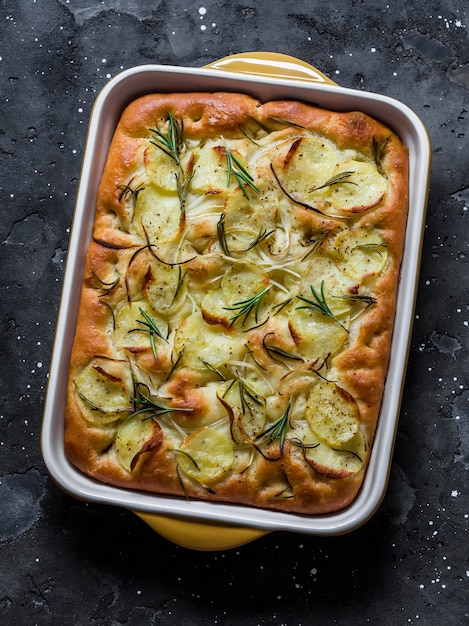 Focaccia mit Kartoffeln und Rosmarin auf einer Draufsicht des dunklen Hintergrundes