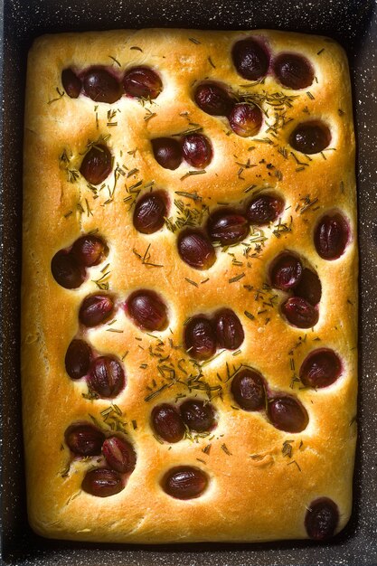 Focaccia mit roten Trauben auf einem blauen Tisch.