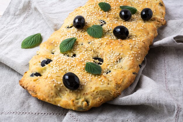 Foto focaccia de pan italiano con oliva, ajo y hierbas en la servilleta de lino