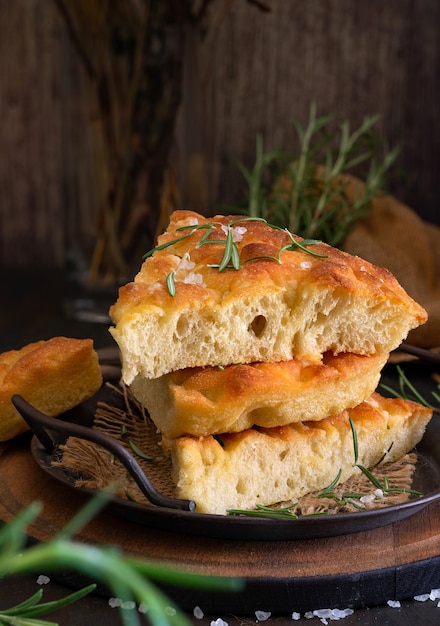 Focaccia de rodajas típicas mediterráneas con aceite de oliva y romero sobre un fondo oscuro