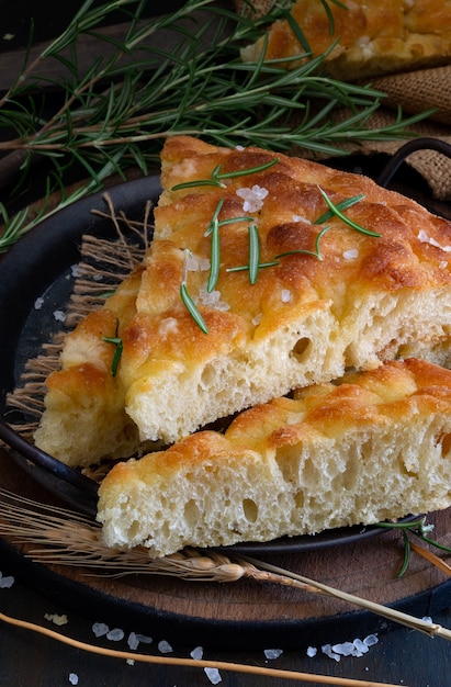 Focaccia de rodajas típicas mediterráneas con aceite de oliva y romero sobre un fondo oscuro