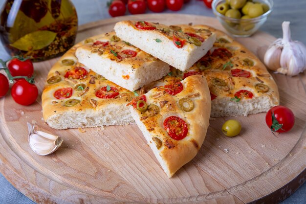 Focaccia con tomate y aceitunas. Pan tradicional italiano. Horneado casero. Primer plano, enfoque selectivo.