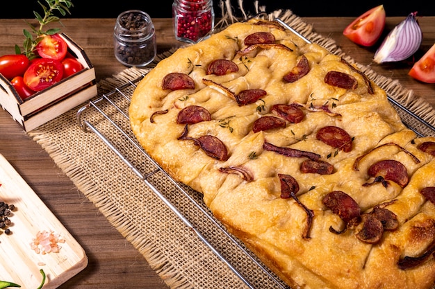 Focaccia tradicional italiana con pepperoni, tomates cherry, aceitunas negras, romero y cebolla - focaccia casera de pan plano.