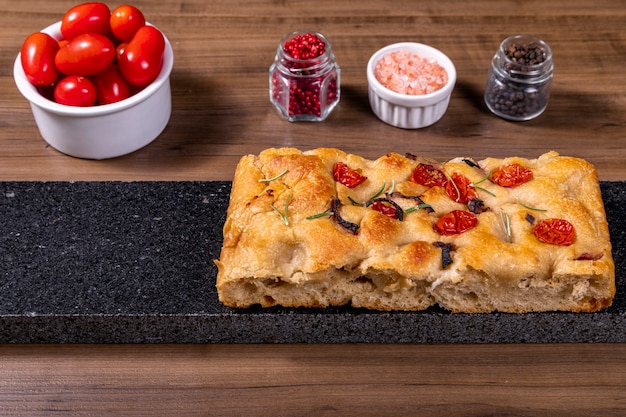 Focaccia tradicional italiana con tomates cherry, aceitunas negras y romero.