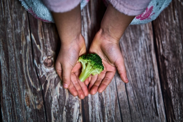 Foto focación selectiva de las manos de una chica con brócoli para una comida saludable