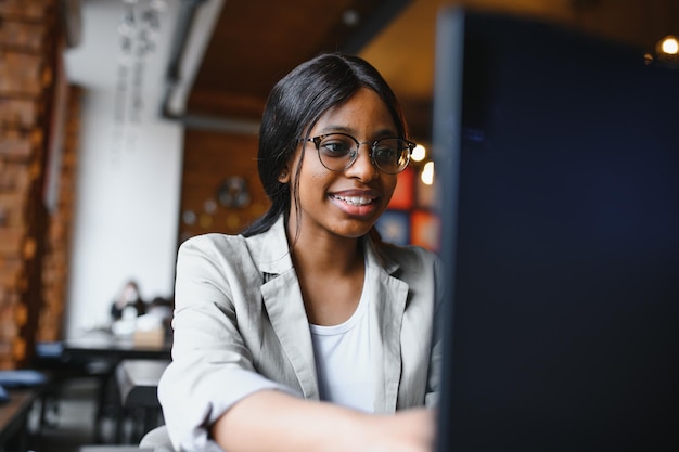 Focada jovem empresária afro-americana ou estudante olhando para laptop mulher negra séria trabalhando ou estudando com computador fazendo pesquisa ou se preparando para o exame on-line