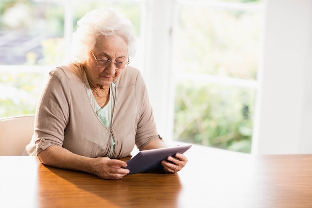 Focada mulher sênior usando tablet em casa