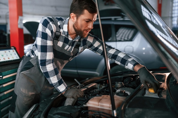 Focado no trabalho Consertando o carro O homem de uniforme está no salão do automóvel