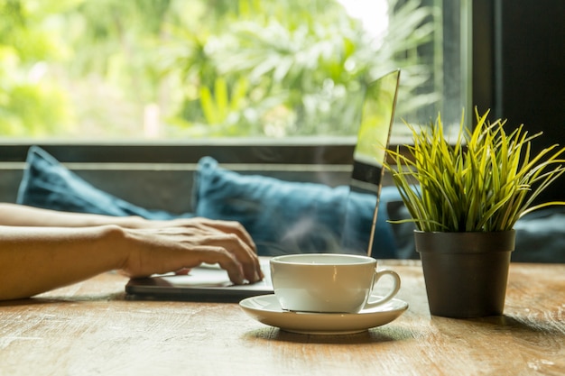 Foco selecionado xícara de café com empresário digitando no laptop teclado