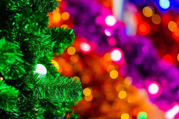 Foco selectivo en el árbol de Navidad verde con bombilla y enfoque borroso de árboles de Navidad coloridos