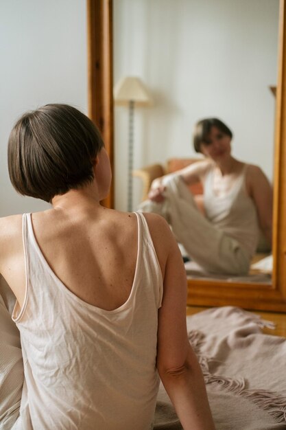 Foto foco selectivo mujer desde la parte de atrás mirándose en el espejo