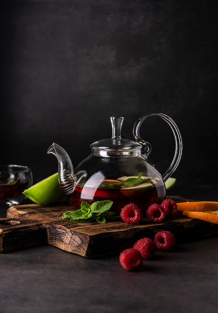 Foco seletivo, chá fresco em bule transparente, com frutas e frutas vermelhas frescas. chá de folhas e especiarias. natureza morta. para publicidade e menus