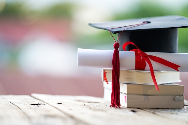 Foco seletivo de close-up de um chapéu de formatura ou papelão e certificado de diploma colocado na mesa