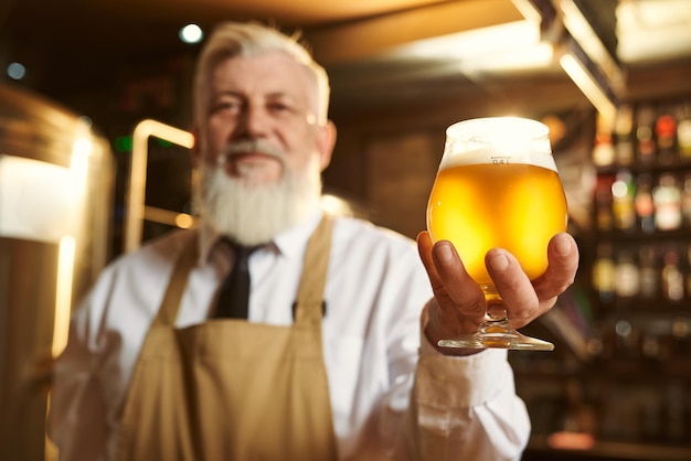 Foto foco seletivo de copo de cerveja light nas mãos do homem mais velho