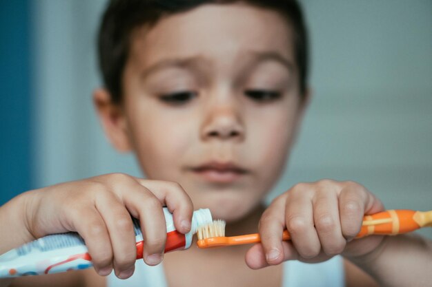 Foco seletivo de menino diligente aplicando creme dental na escova de dentes