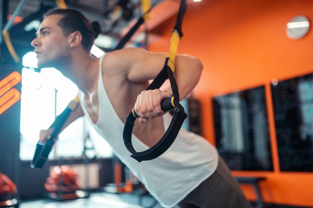 Foco seletivo de uma mão masculina segurando a alça de fitness