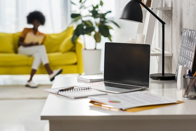 Foco seletivo do laptop na mesa e freelancer americano africano em home office