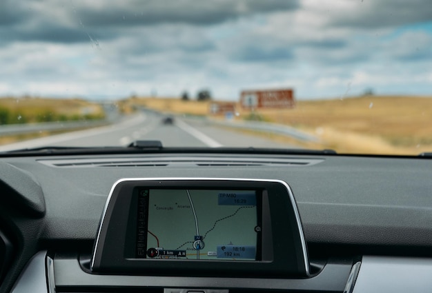 Foco seletivo do navegador GPS integrado no painel de um carro descendo a estrada cênica no Algarve Portugal