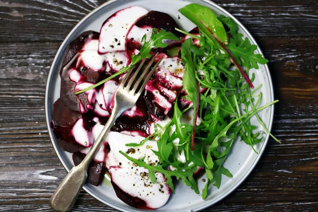 Foco seletivo. Macro. Comida vegana. Salada de rúcula de beterraba em um prato com molho de iogurte e azeite. Comida saudável. Salada de dieta.