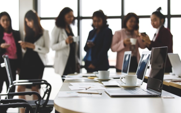 Foco seletivo na mesa de trabalho, grupo de empresárias irreconhecíveis que estão juntas no escritório no momento do intervalo. Trabalho em equipe de funcionária tomando com relaxar em desfocar o fundo.