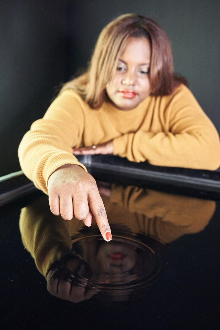 Foto foco seletivo na mulher afro-americana tocando o reflexo de seu rosto na água