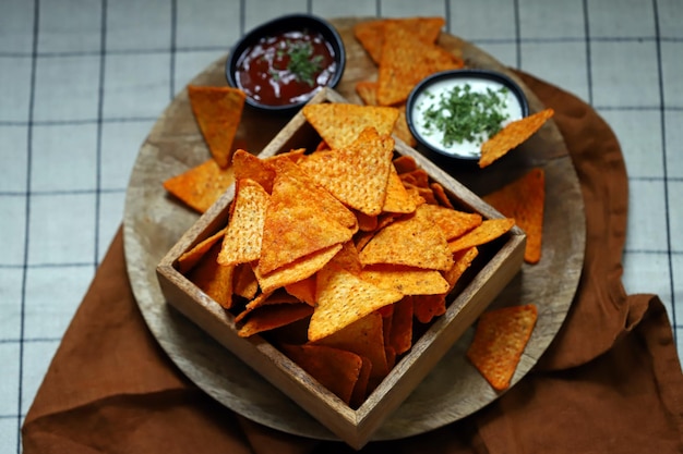 Foco seletivo Nachos de chips de milho em uma tigela de madeira com molhos