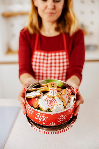 Foco seletivo nas mãos com caixa cheia de biscoitos de gengibre feitos para véspera de natal