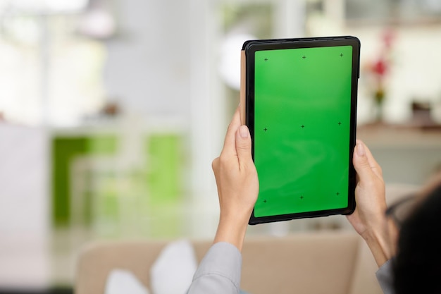 Foco seletivo nas mãos da mulher e tablet com tela verde em branco