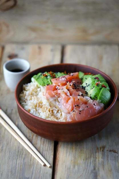 Foco seletivo. Poke tigela com salmão e abacate. Comida saudável. Arroz com abacate e peixe. Tigela de sushi.