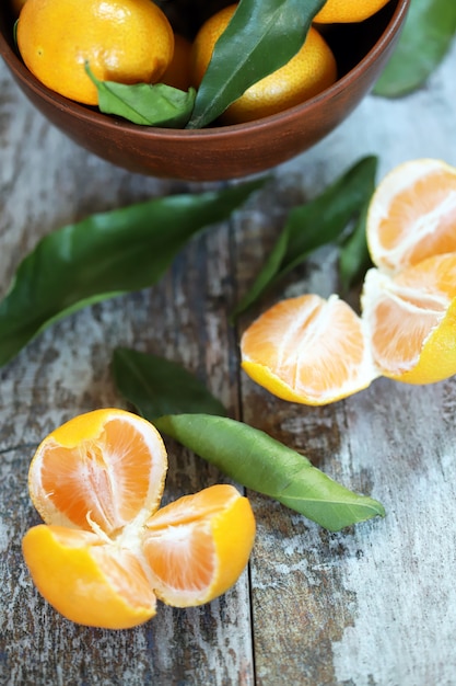 Foco seletivo. Tangerinas suculentas maduras em uma tigela. Folhas de tangerina. Mandarinas perfumadas frescas. Colher tangerinas.