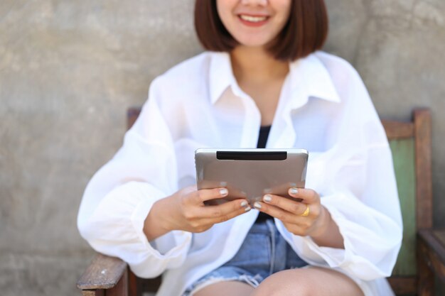 Foco suave de mulher mão segurando tablet dispositivo inteligente com a digitação de mensagem ou verificação newsfeed em redes sociais