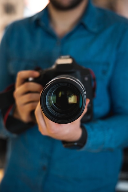 Foco superficial de um jovem fotógrafo segurando uma câmera dsrl moderna