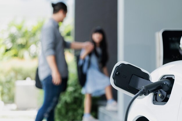 Focus EV car recargando la batería en casa con gente progresista en segundo plano